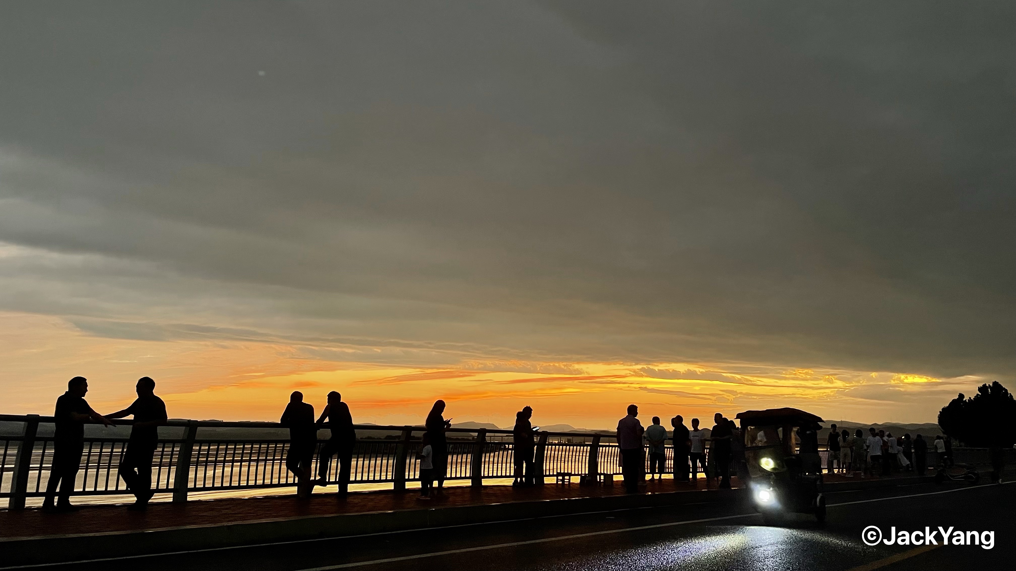 People silhouetted against a vivid sunset beside the water